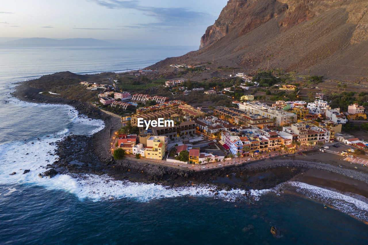 Spain, valle gran rey, drone view of town at edge of la gomera island at dusk