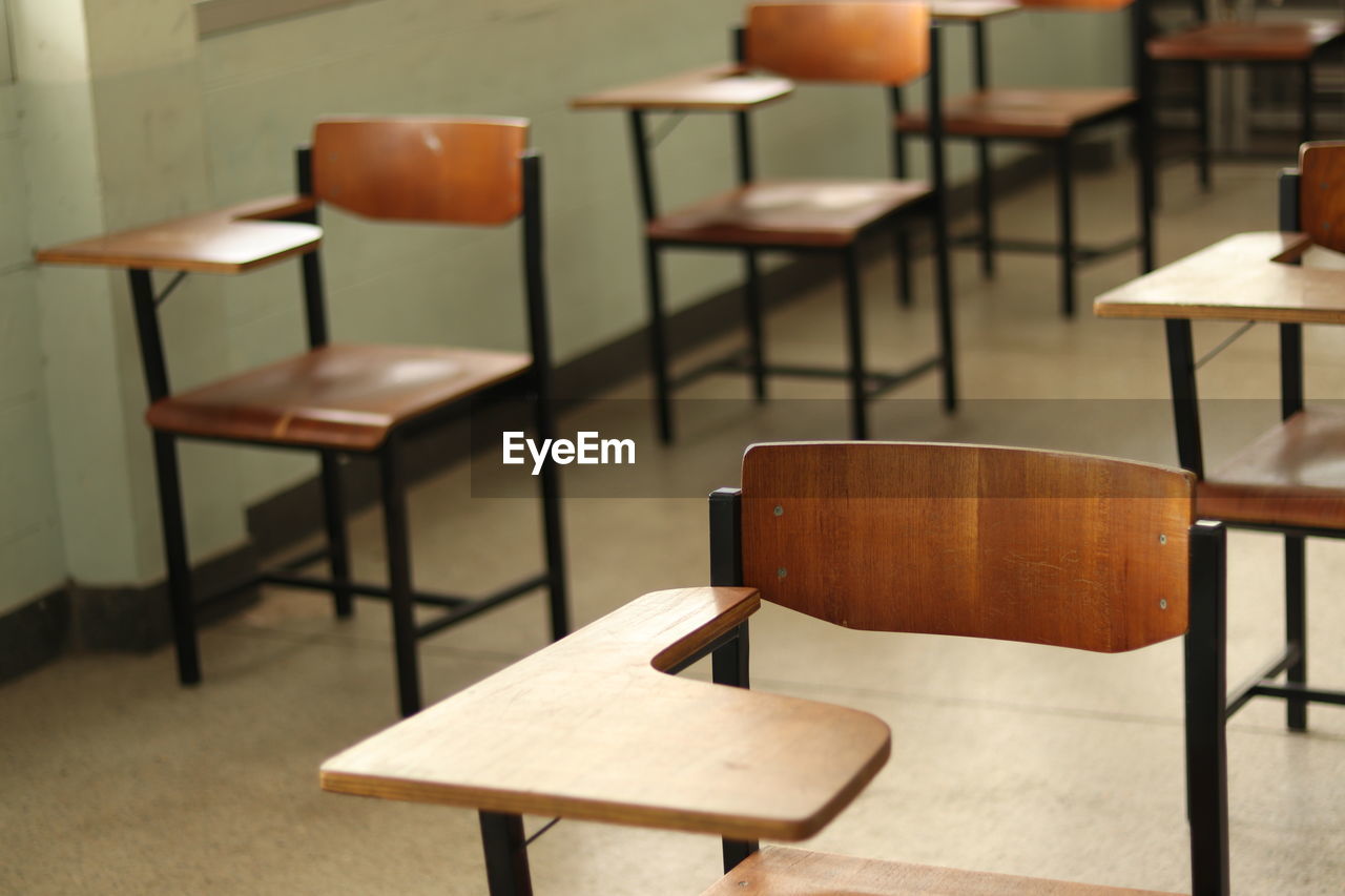 Some wooden student chair in a classroom with blur background
