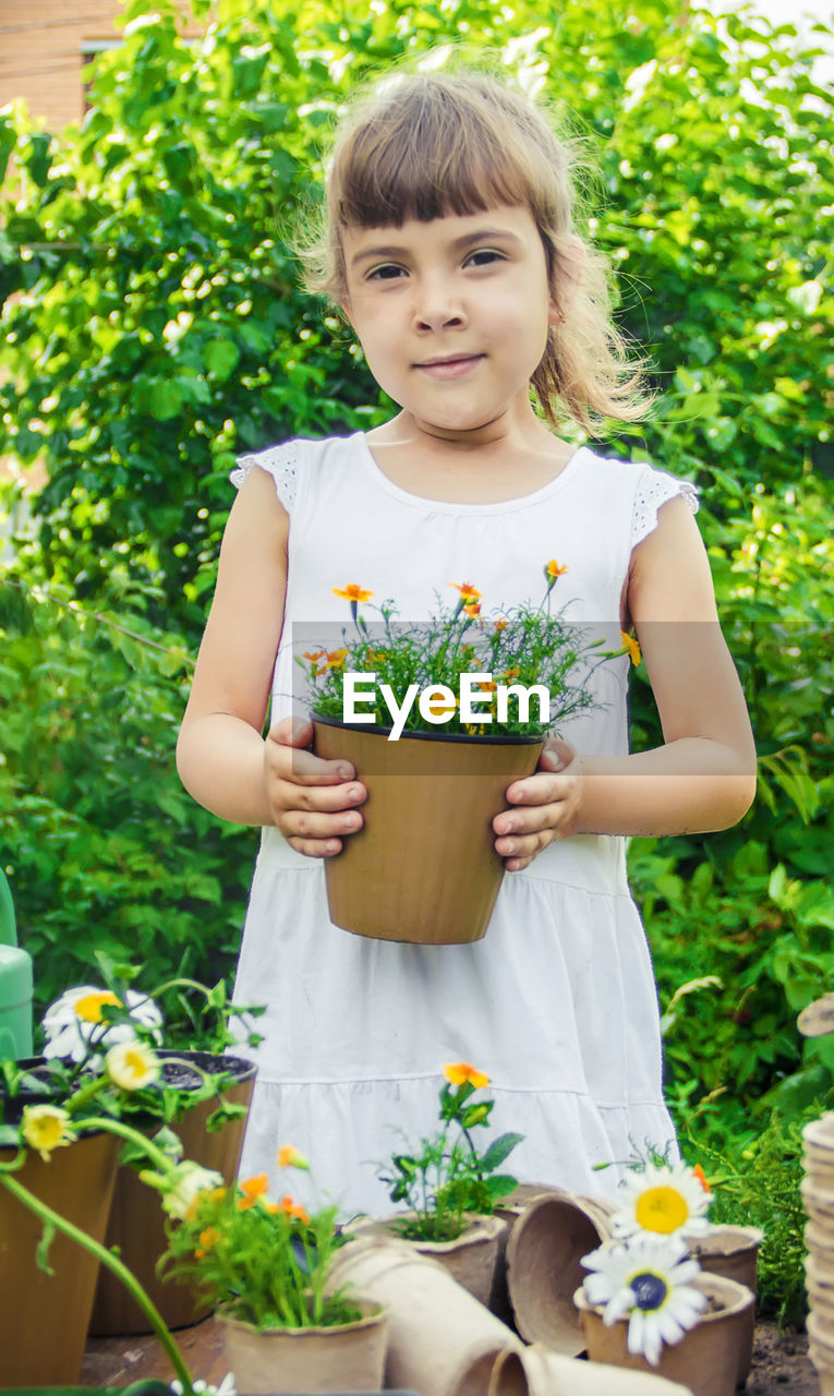 portrait of smiling young woman holding potted plant