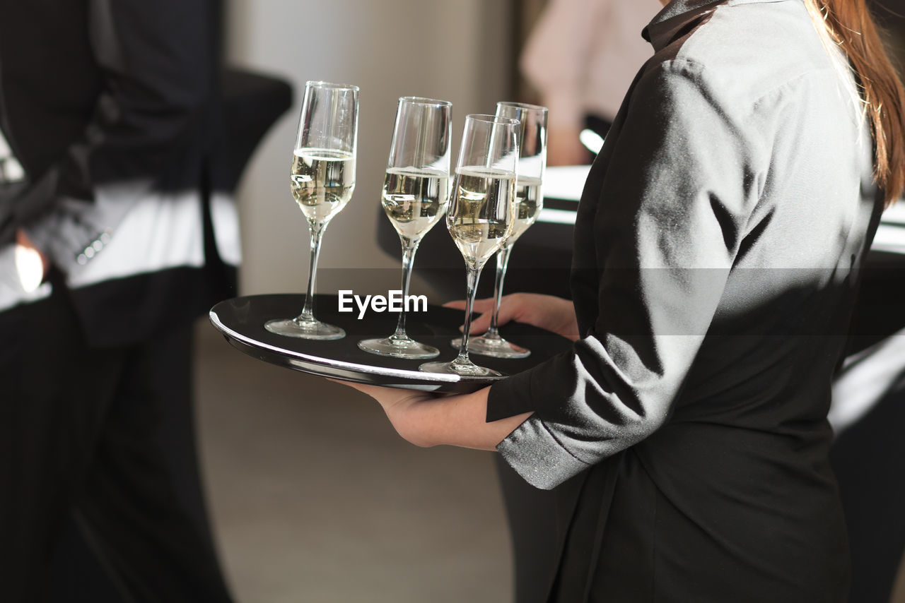 Midsection of waitress serving drinks