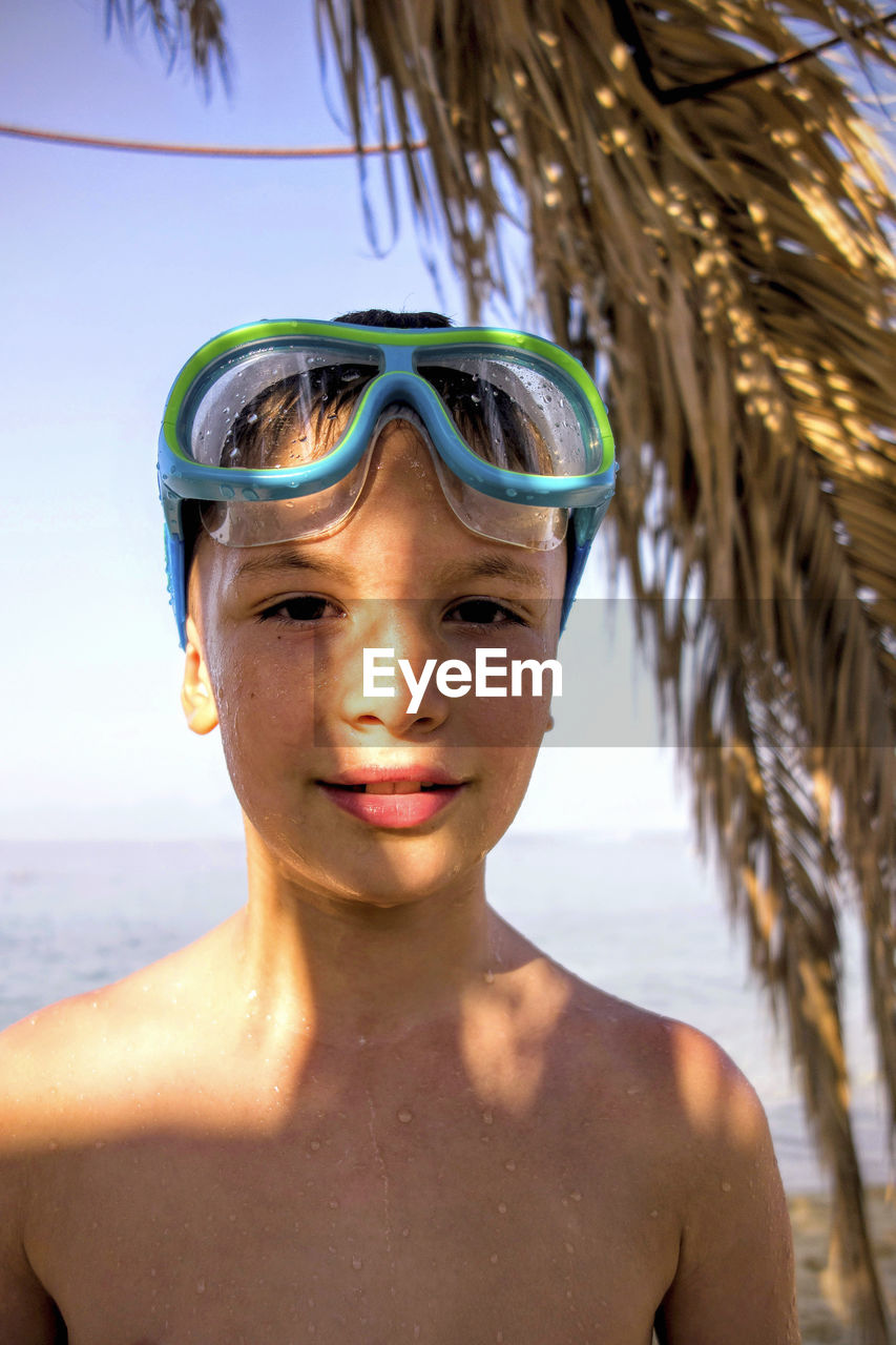 Portrait of wet shirtless boy wearing swimming goggles