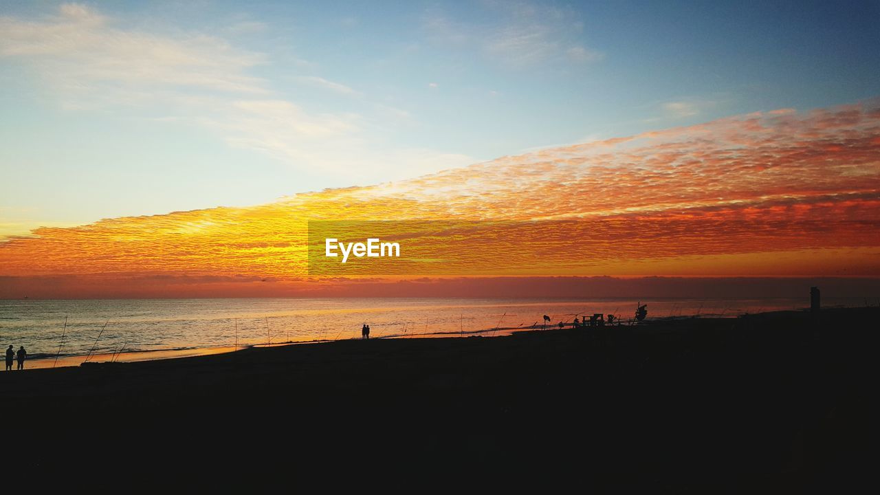 SCENIC VIEW OF BEACH AGAINST SKY AT SUNSET