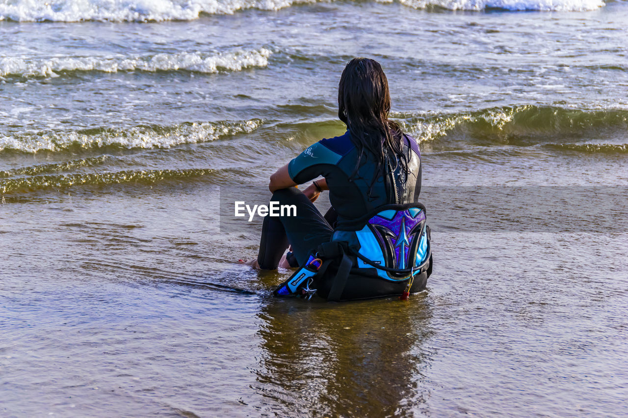 Rear view of woman sitting at beach