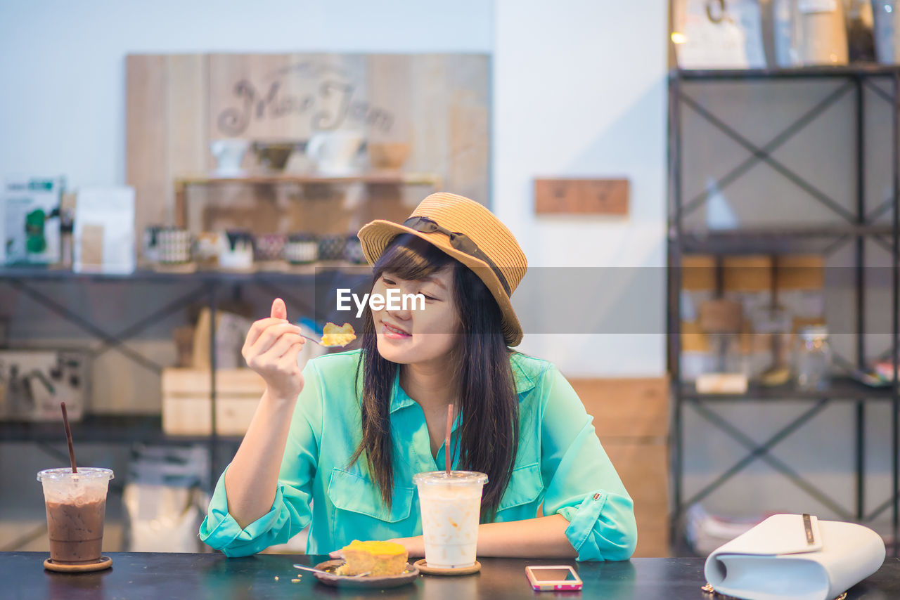 PORTRAIT OF YOUNG WOMAN SITTING AT TABLE