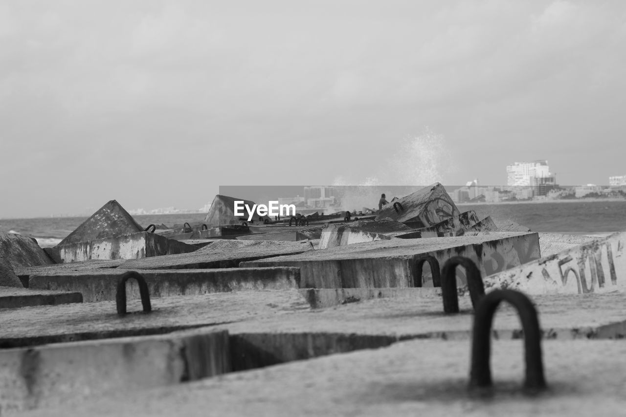 OLD ABANDONED CAR ON FIELD AGAINST SKY