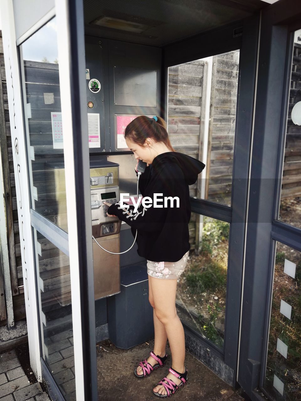 Teenage girl talking on telephone in booth