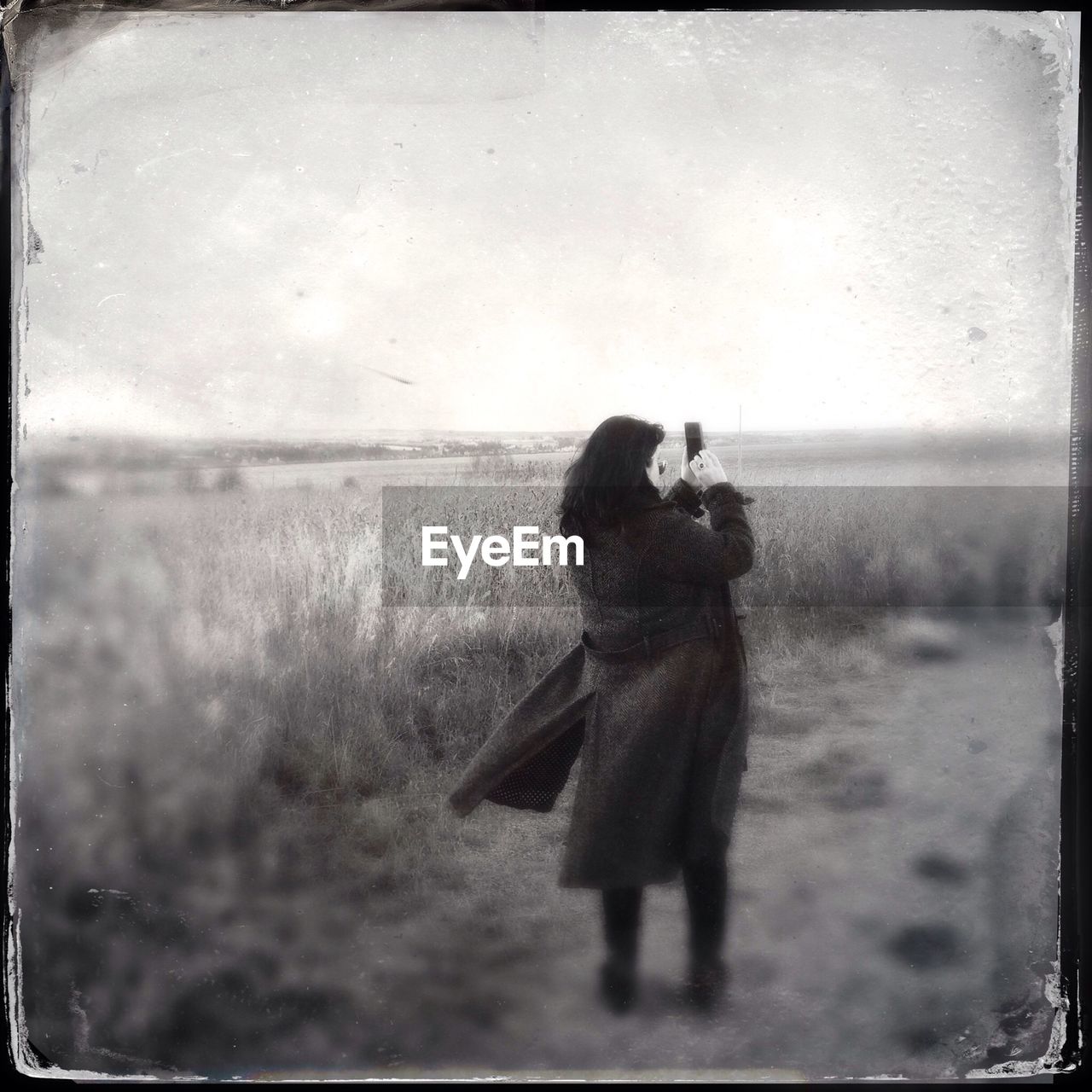 Rear view of woman photographing countryside landscape