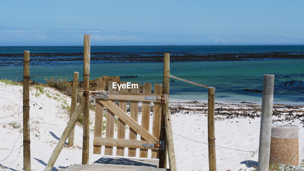 Wooden posts on beach against sky