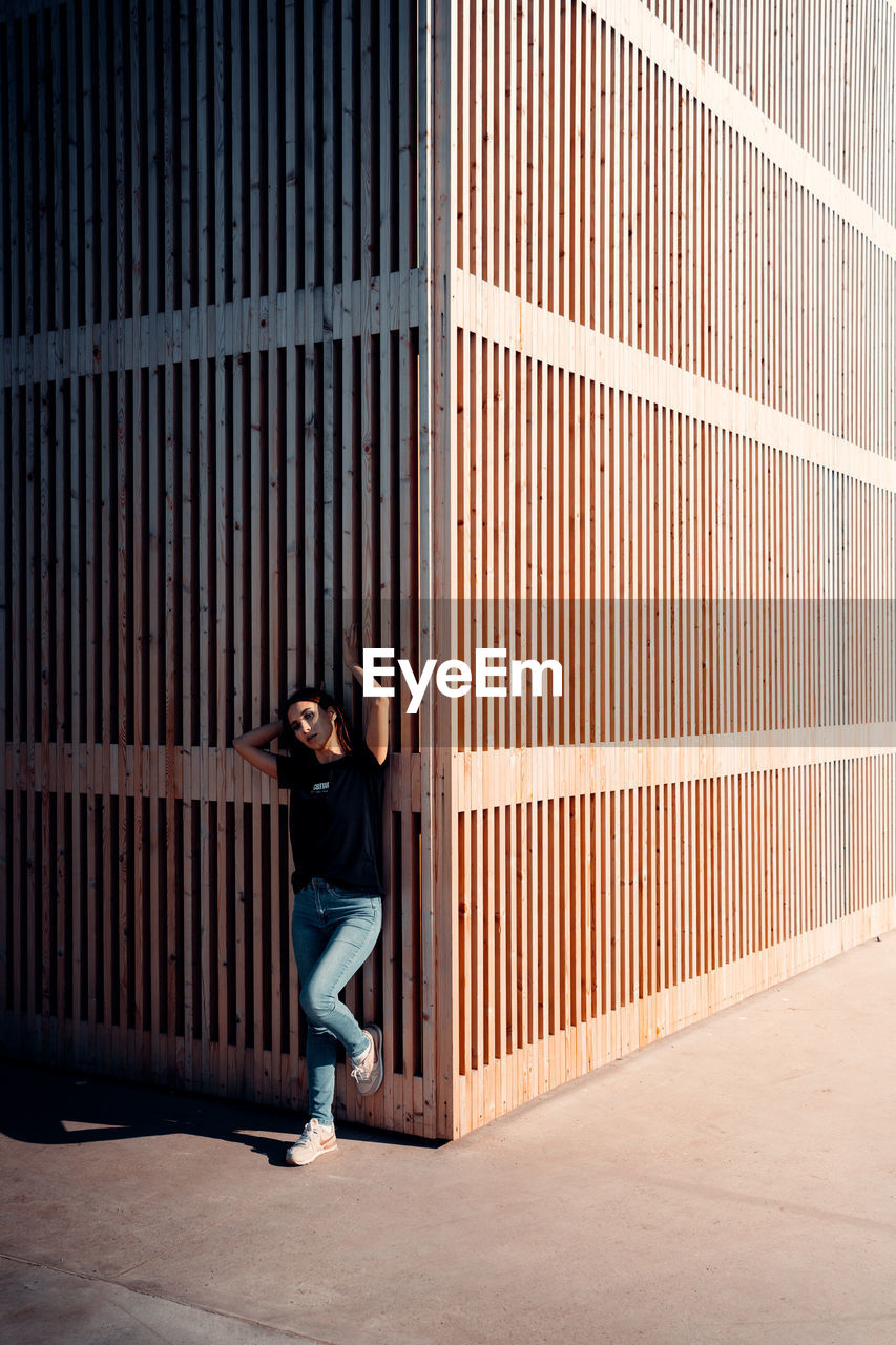 PORTRAIT OF WOMAN STANDING AGAINST BUILDING