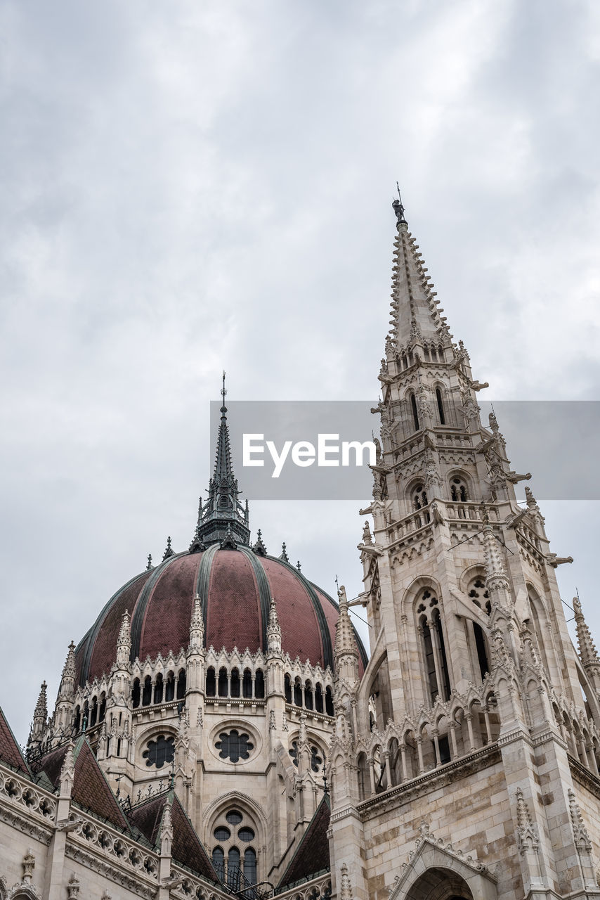 Low angle view of hungarian parliament building against cloudy sky