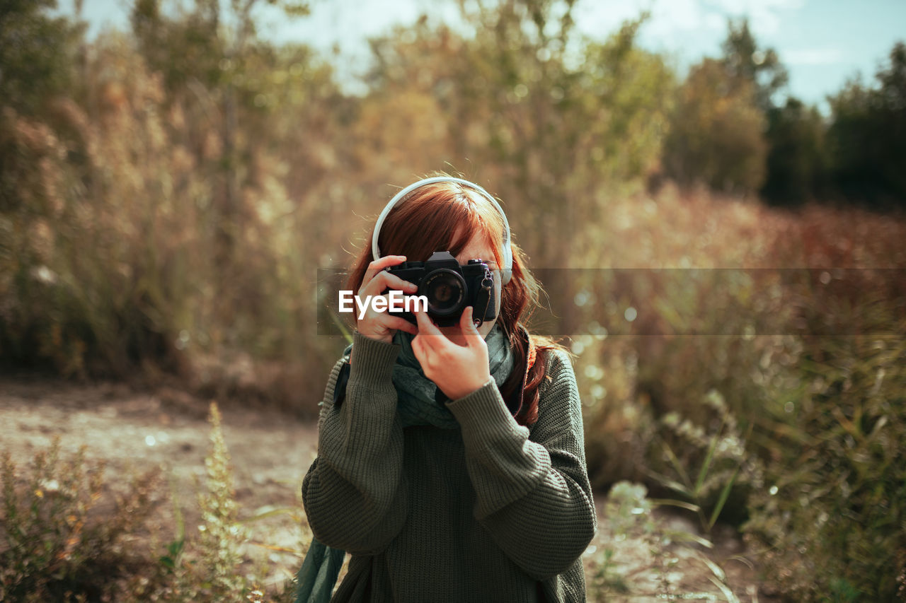 Woman holding camera while standing during winter