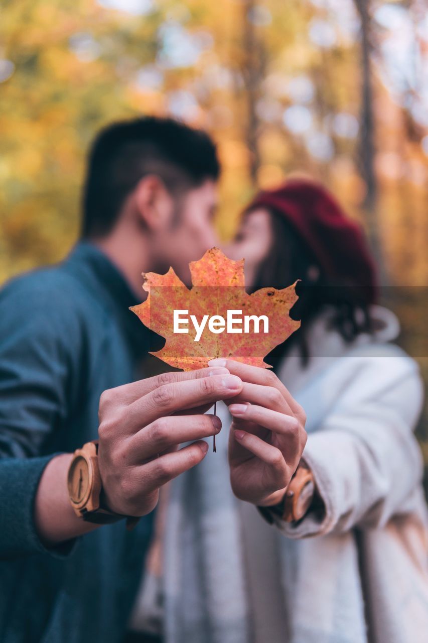 Couple kissing while holding maple leaf