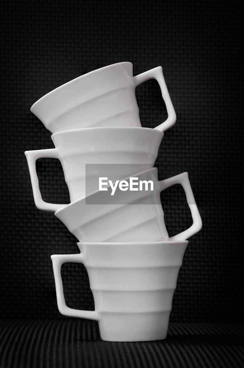 Photo of 4 stacked white cups against a black background