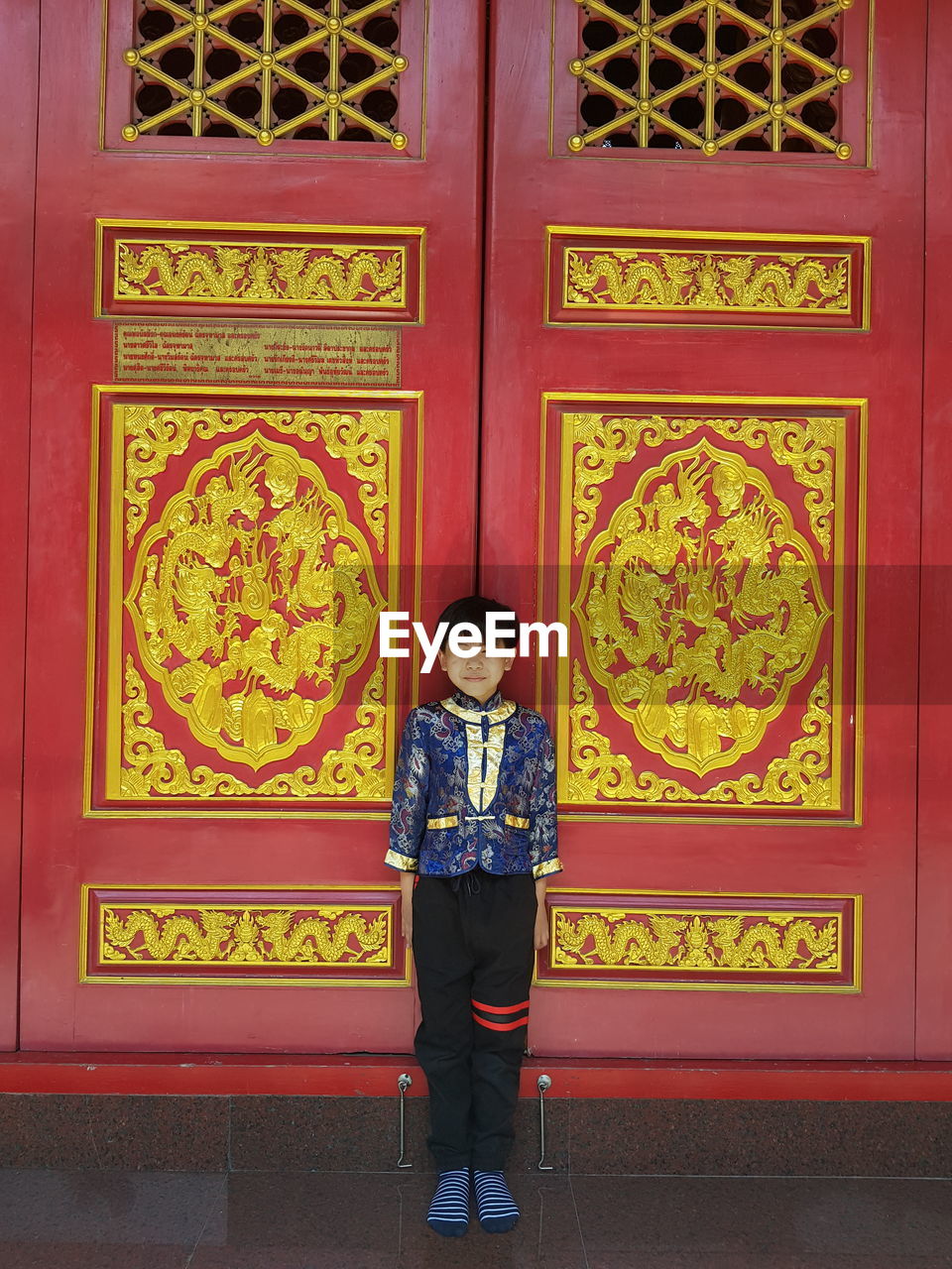 Full length of boy standing against closed door