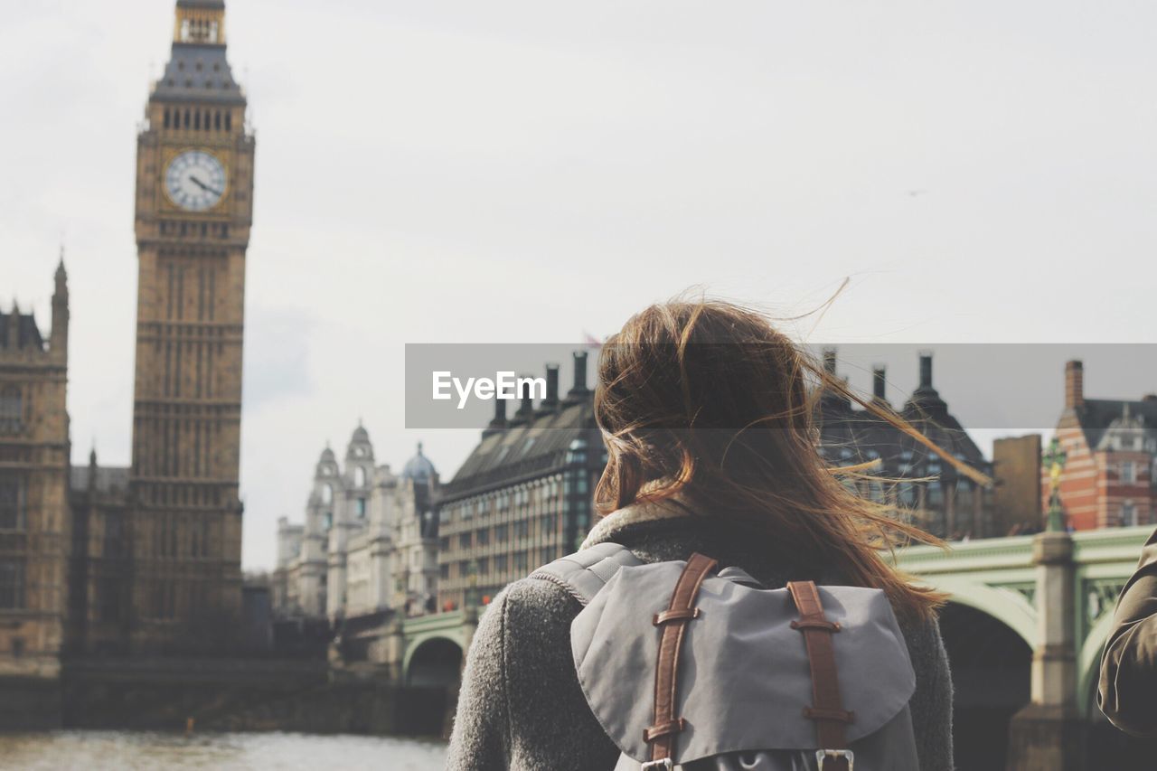 Rear view of woman looking big ben while standing by thames river