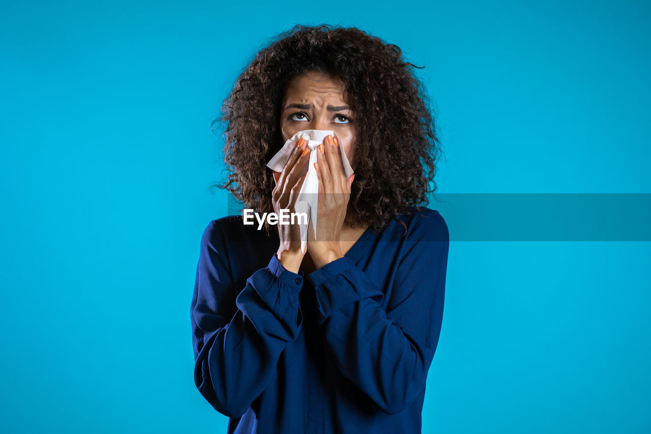 PORTRAIT OF A YOUNG WOMAN AGAINST BLUE BACKGROUND