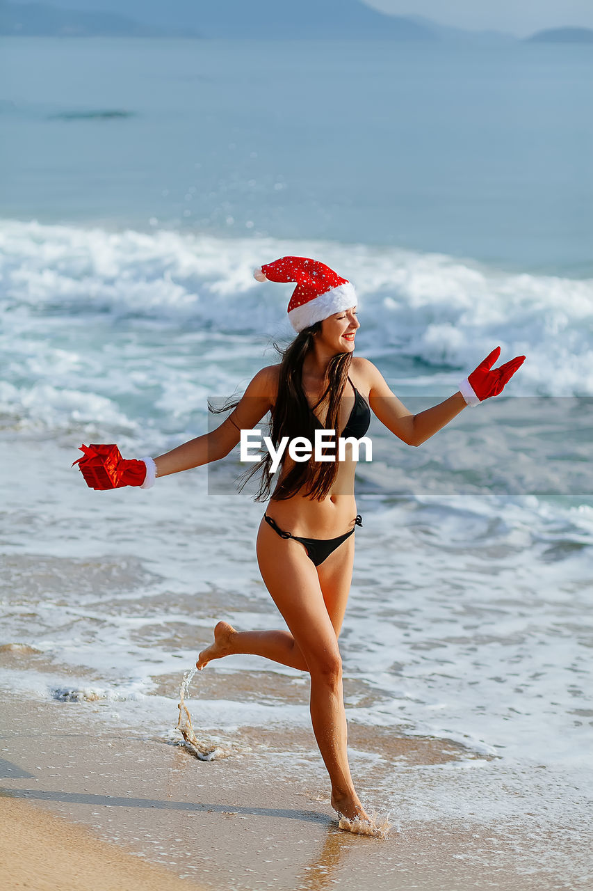 Happy young woman wearing bikini running at beach