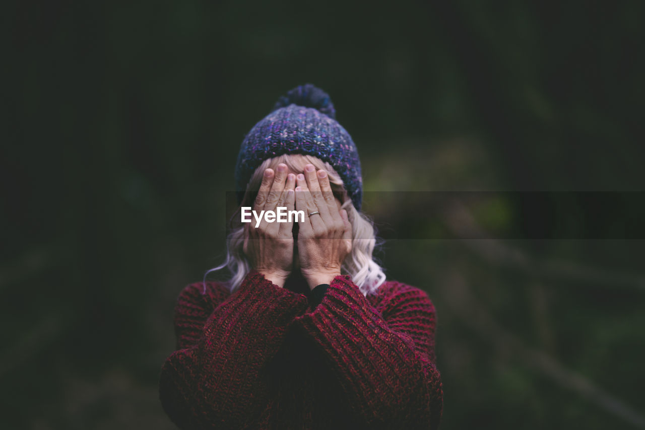 Woman covering face with hands in forest