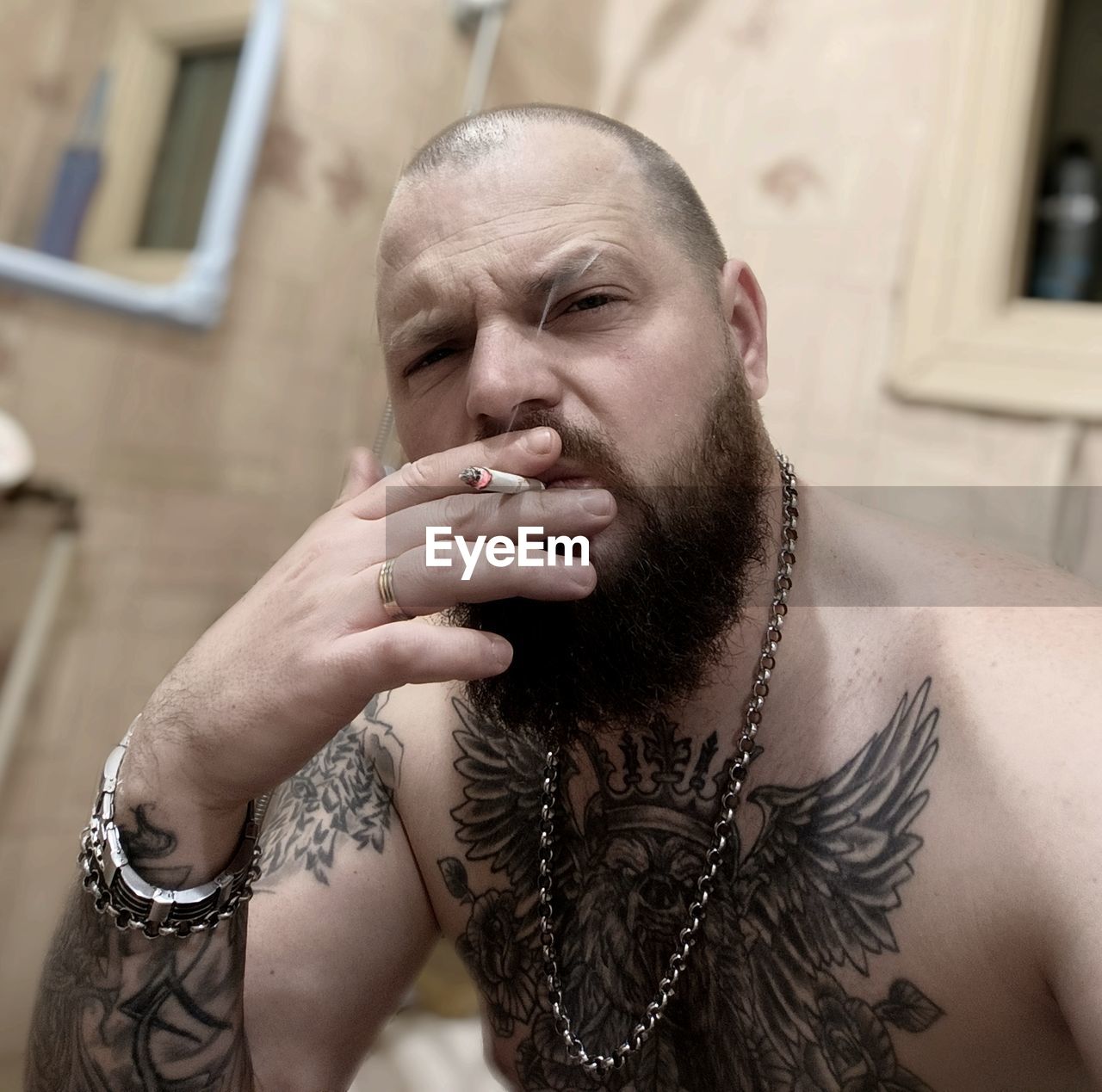 adult, facial hair, one person, tattoo, beard, men, portrait, human hair, person, jewelry, headshot, hairstyle, lifestyles, individuality, chest hair, architecture, hand, front view, social issues, human head, young adult, focus on foreground, indoors, smoking