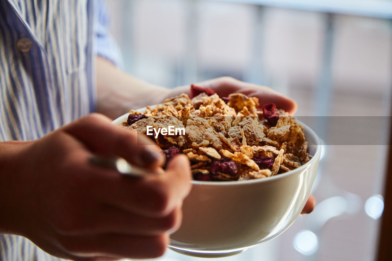 Young woman having breakfast next to a window at home