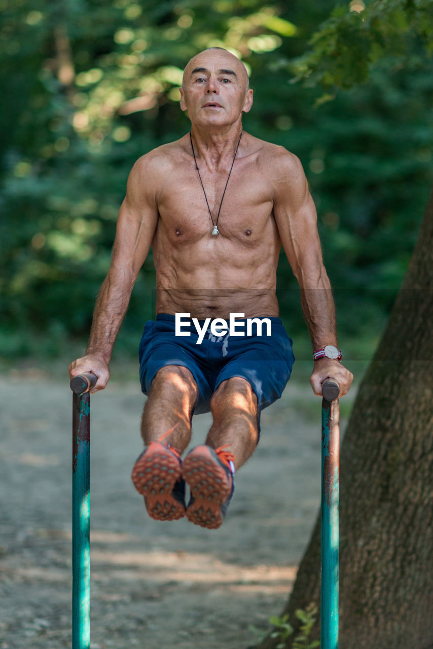 Portrait of shirtless man exercising in park