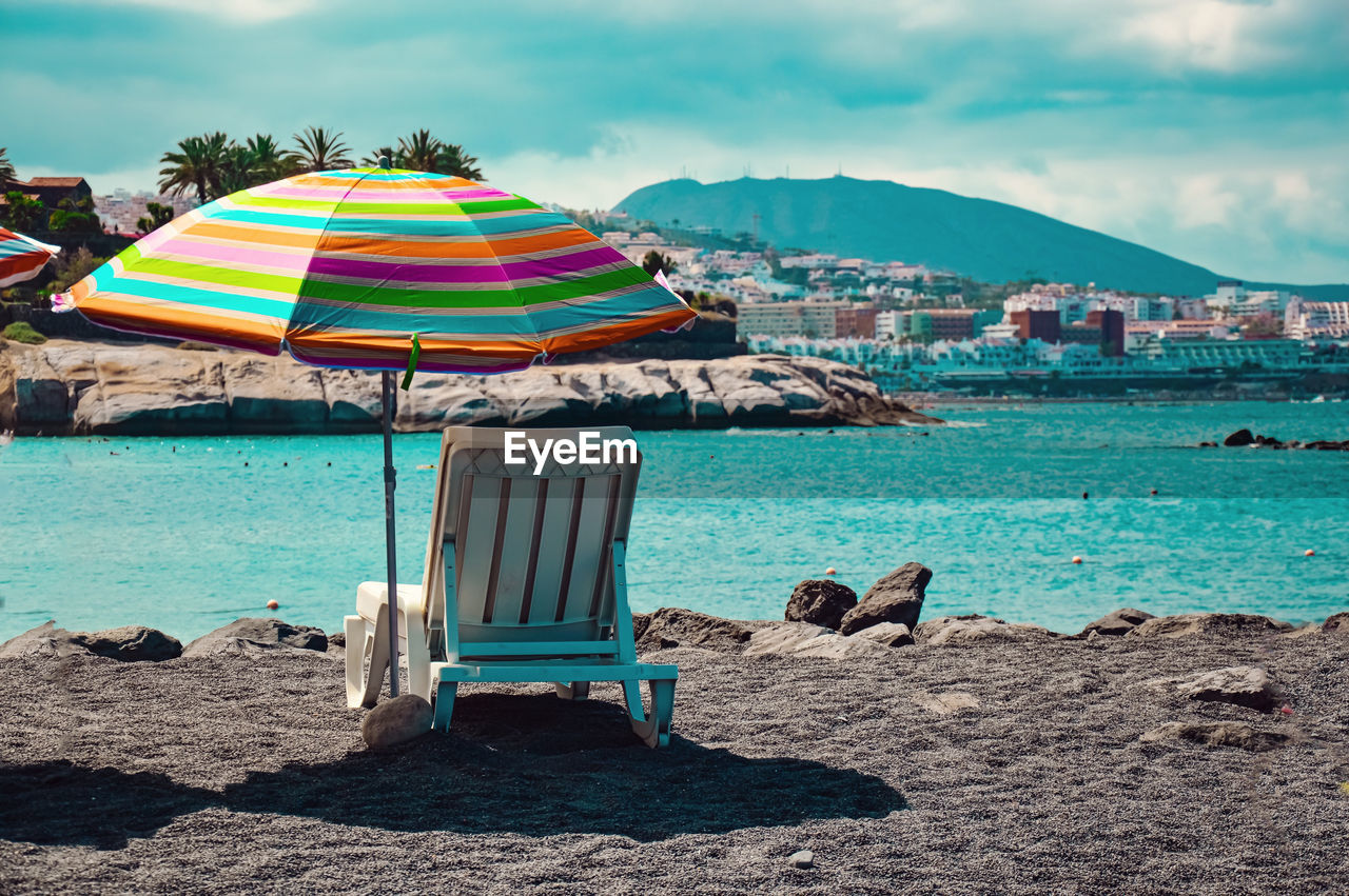 DECK CHAIRS ON BEACH AGAINST BUILDINGS