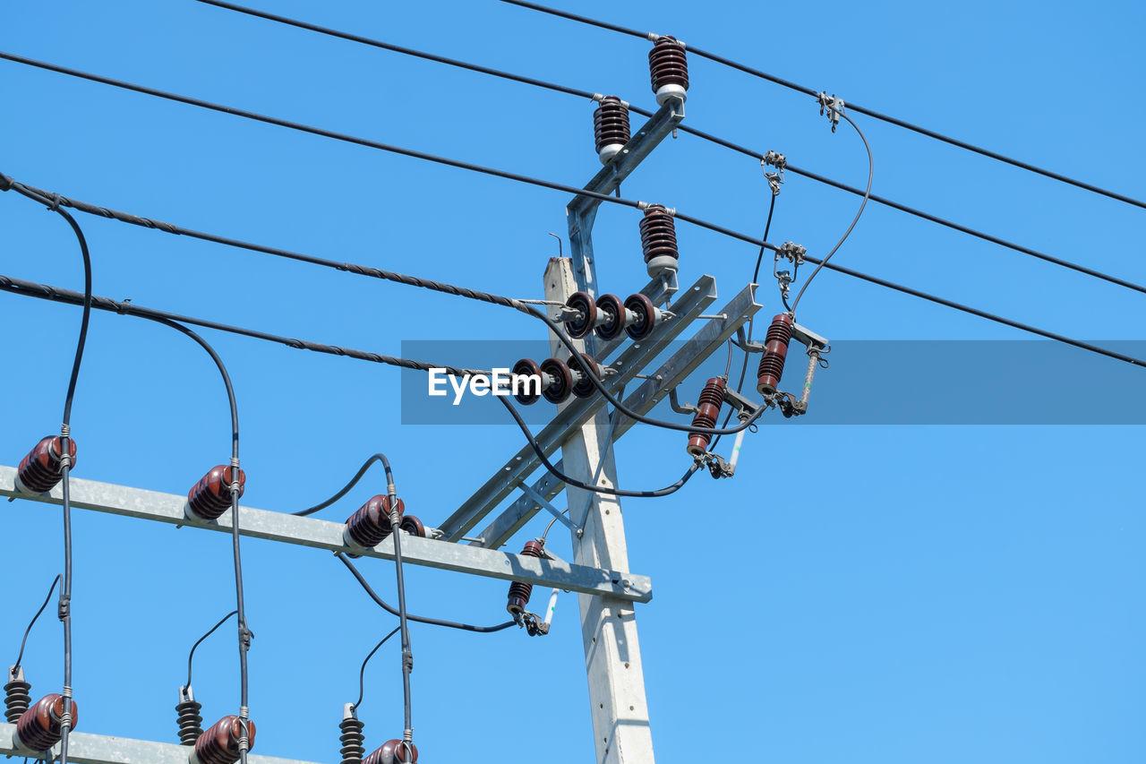 Low angle view of electricity pylon against blue sky