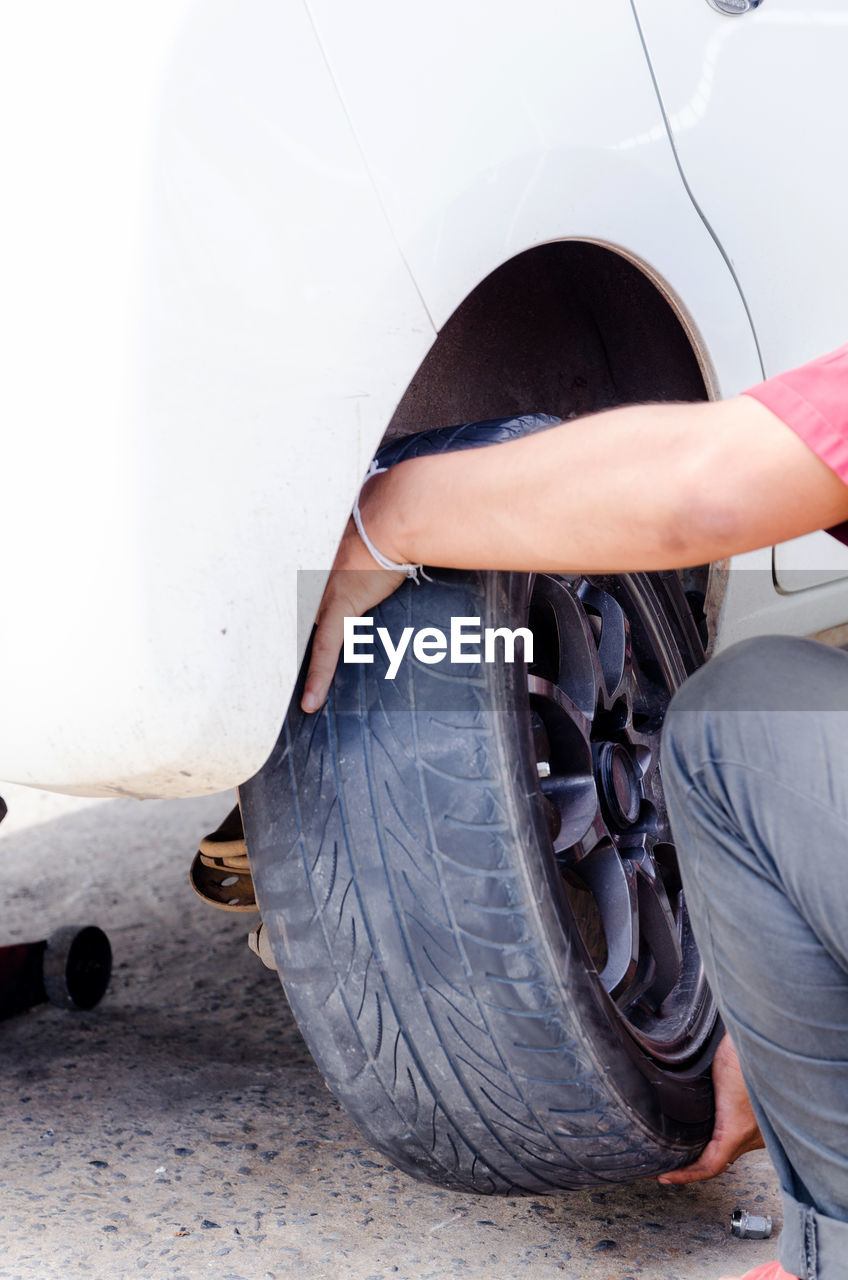 Cropped image of man repairing tire on road