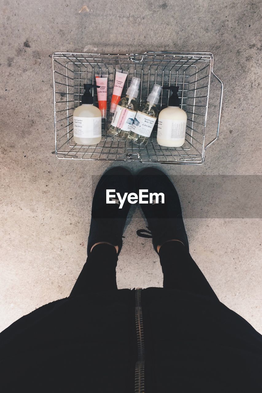 Low section of person standing by shopping basket