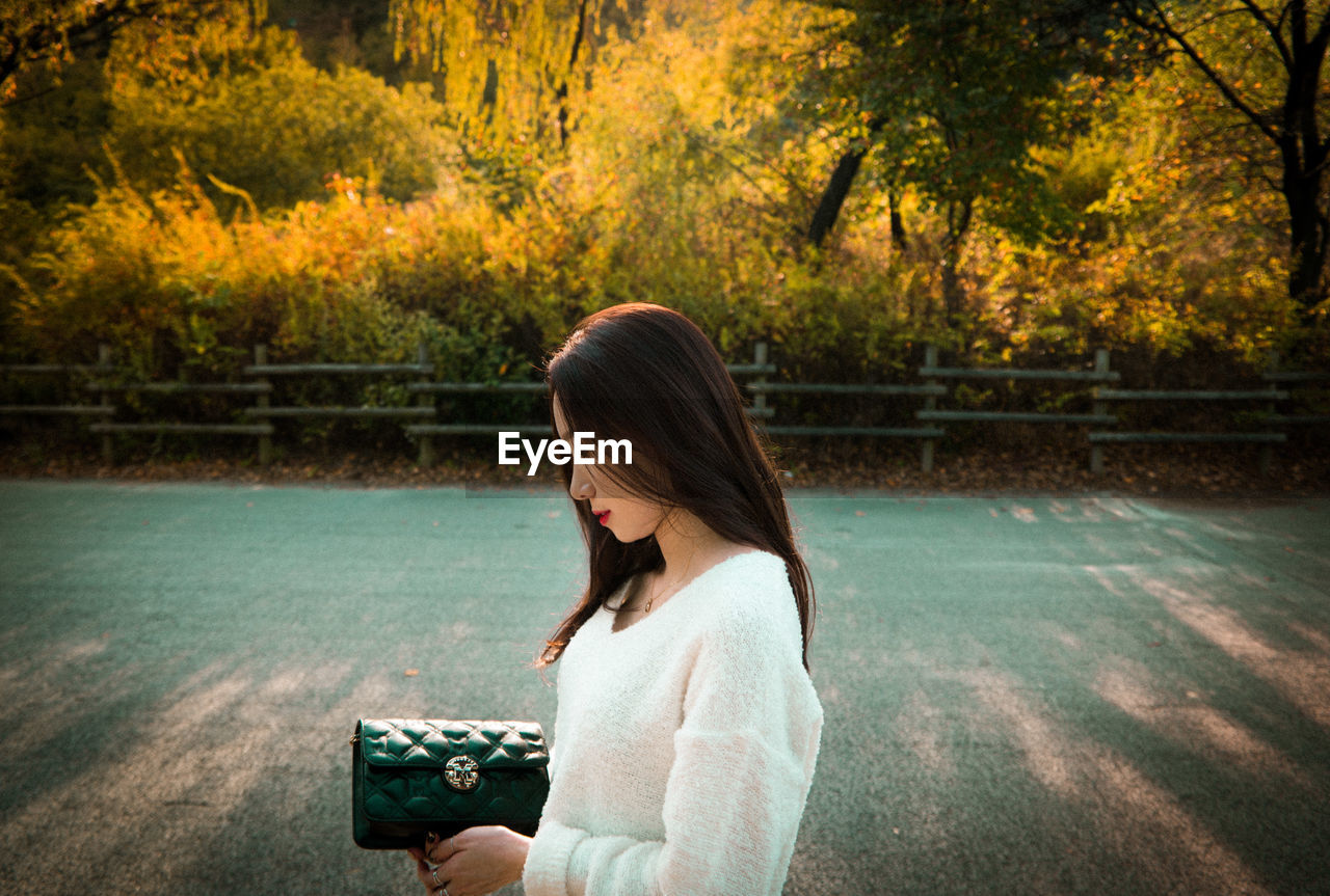 Side view of woman standing on road during autumn