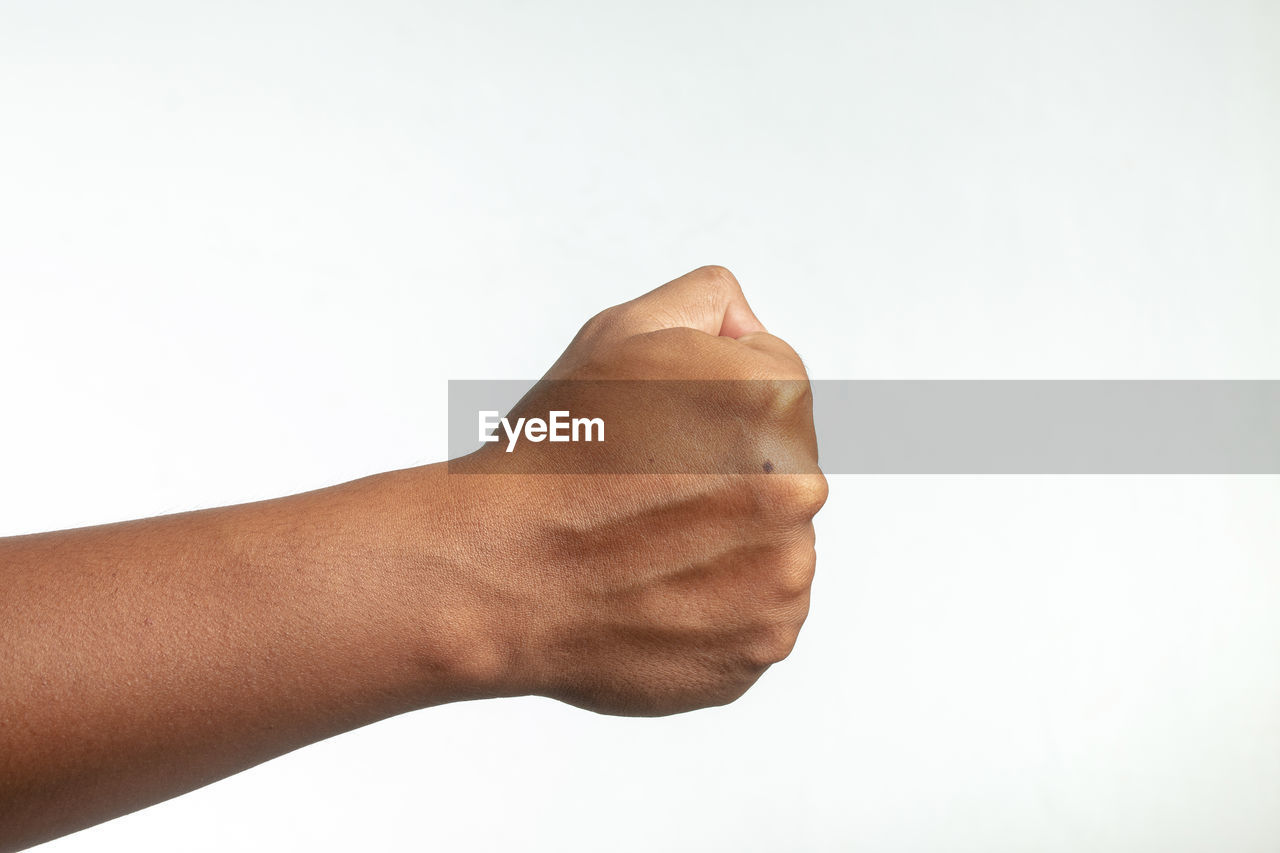 Cropped image of hand clinching fist against white background