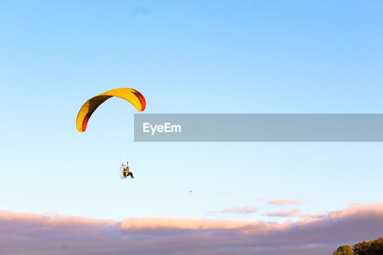 Low angle view of man powered paragliding against sky