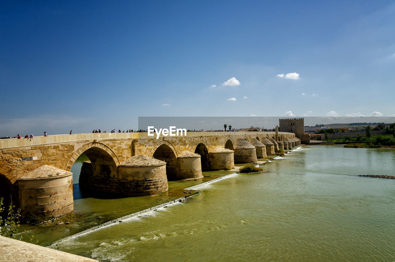 Arch bridge over river against sky