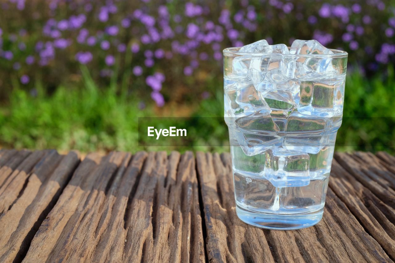 GLASS OF WATER ON TABLE AGAINST BLURRED BACKGROUND