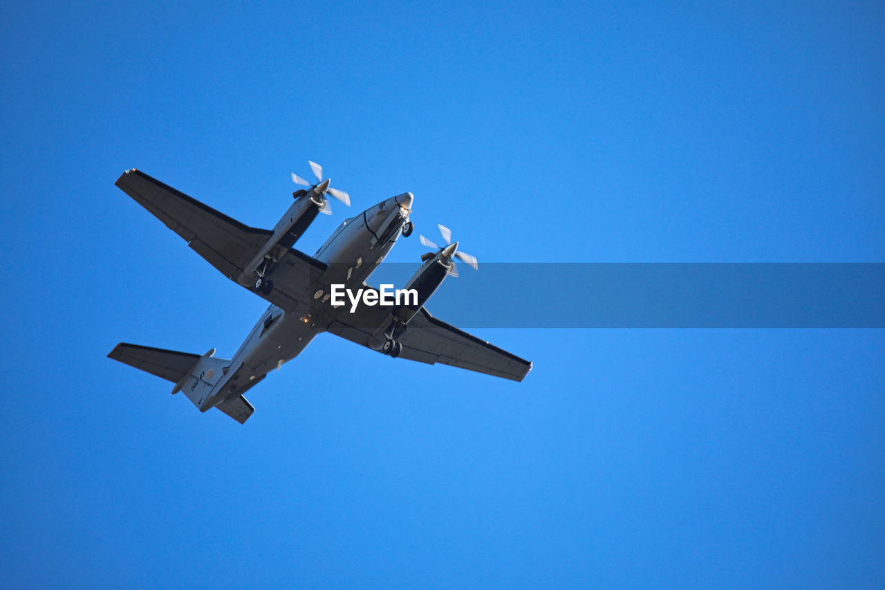 Low angle view of airplane against clear blue sky