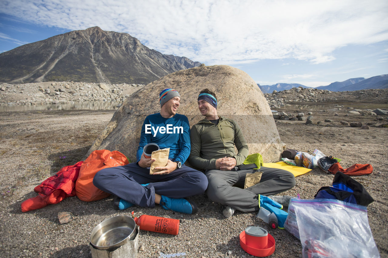 Climbing partners share a laugh during mealtime at campsite.