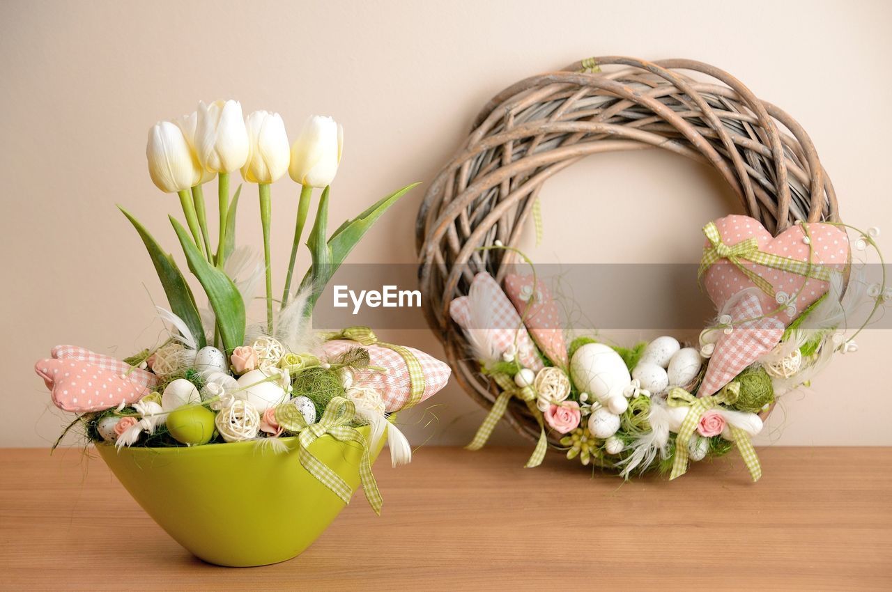 POTTED PLANT IN BASKET ON TABLE AGAINST WALL