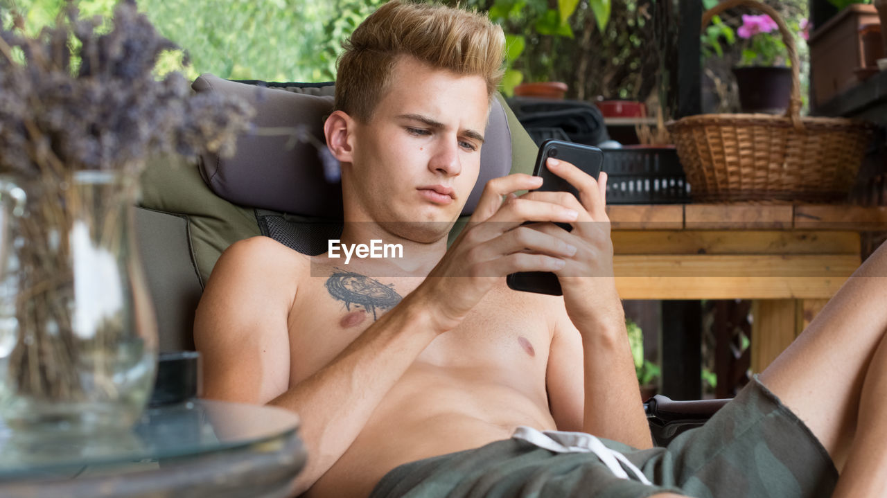 Young man, uses technology on his mobile phone on the terrace at