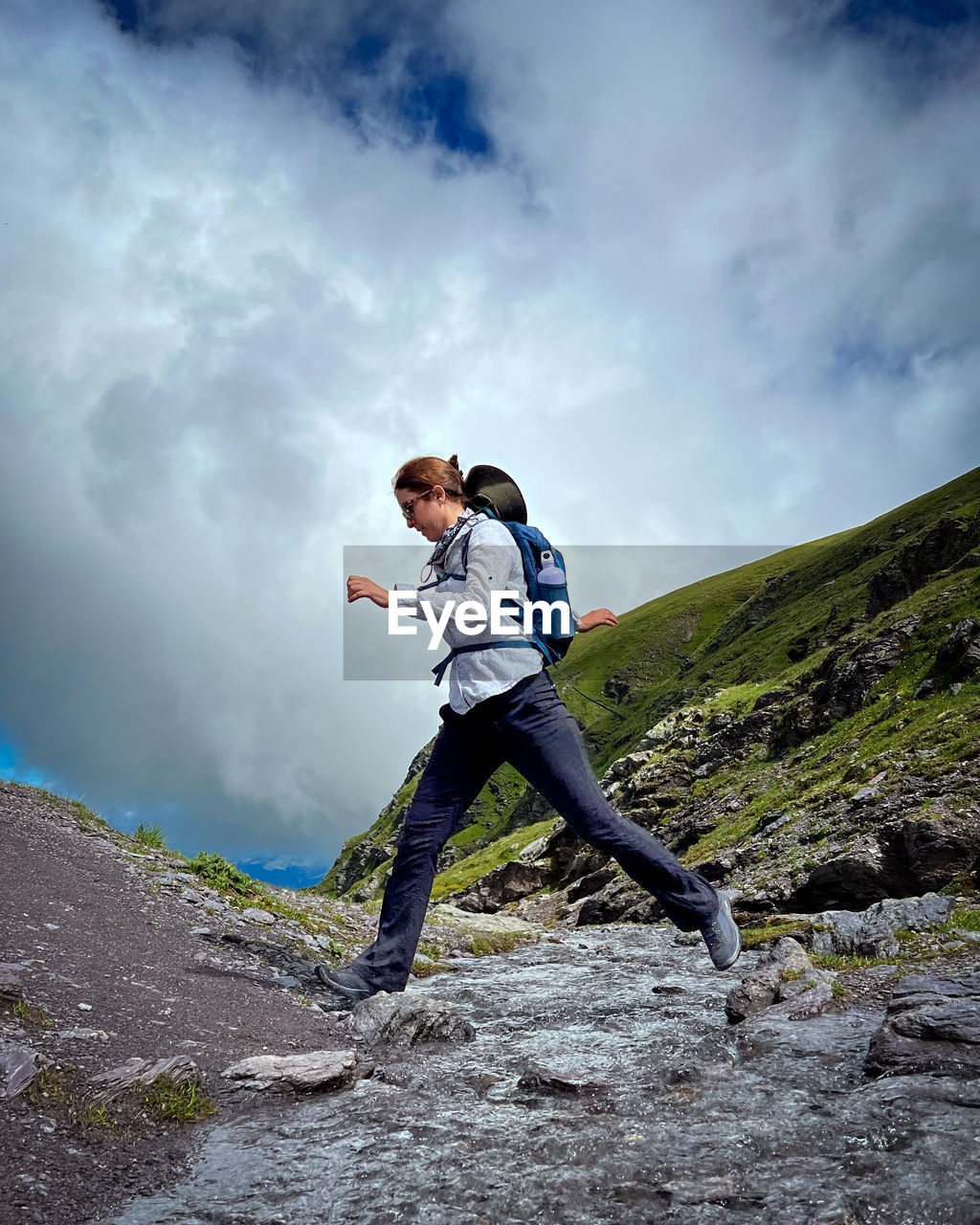 Full length of woman jumping across a stream