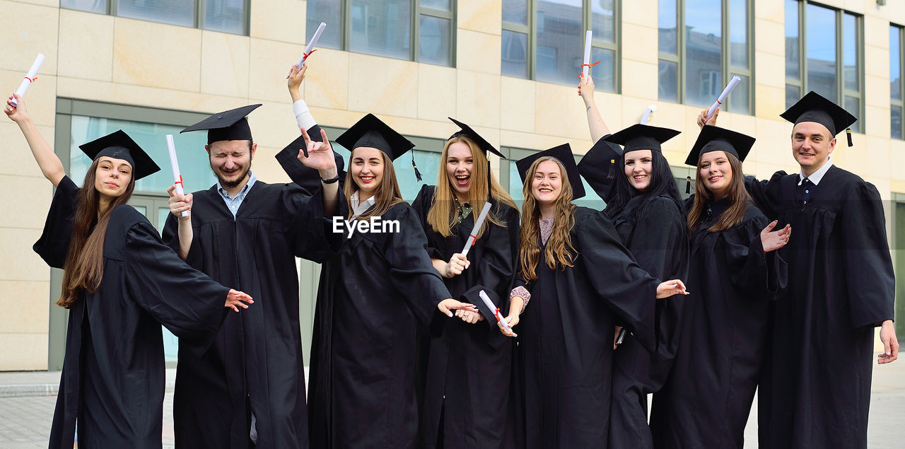 Cheerful friends wearing graduation gown
