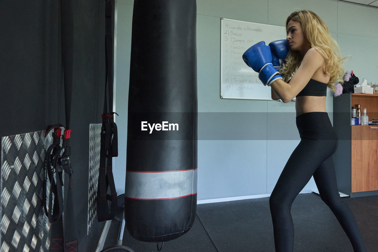 Side view of confident female boxer exercising in gym