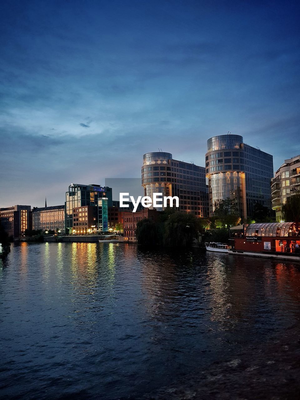 River by buildings against sky at dusk