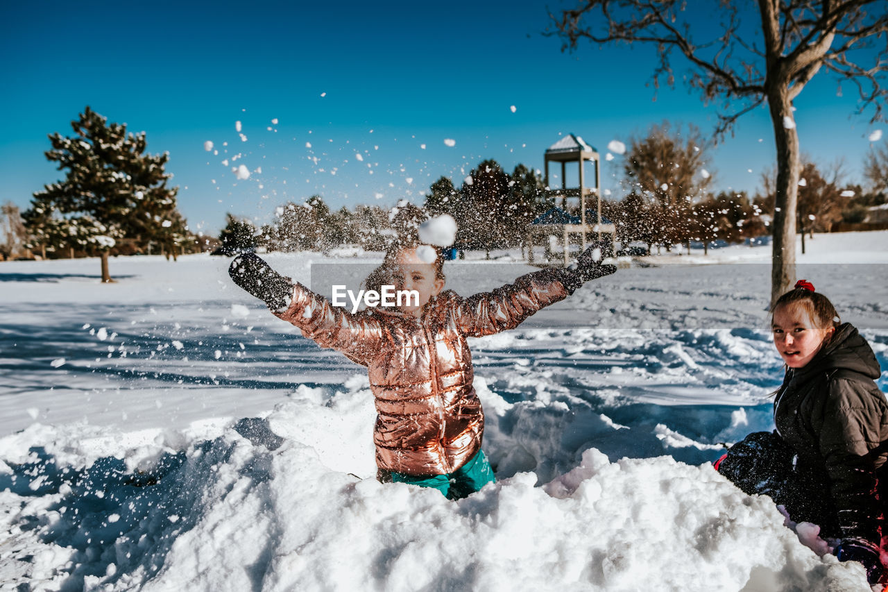 Action shot of young girl throwing a snowball during winter
