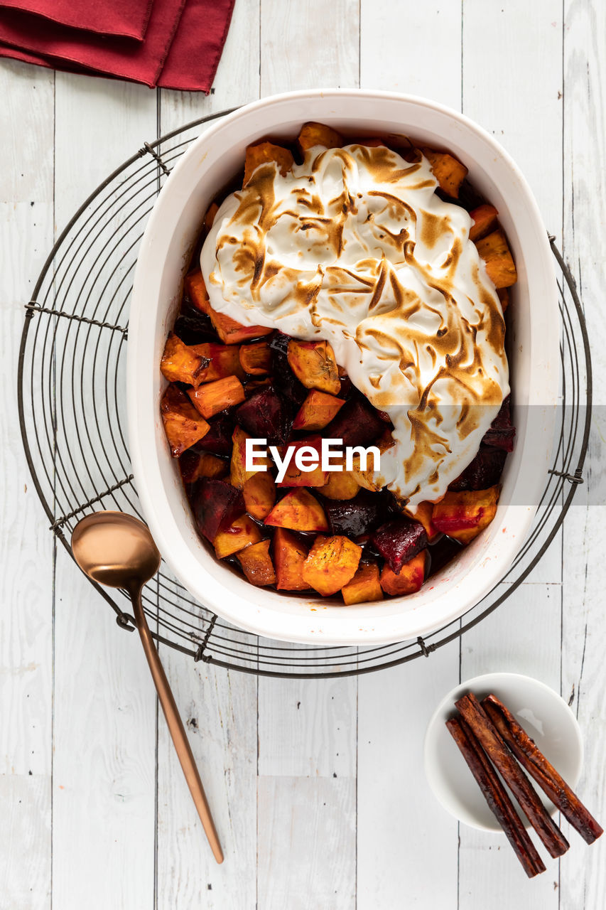 A casserole dish filled with merengue topped baked sweet potatoes and beets.