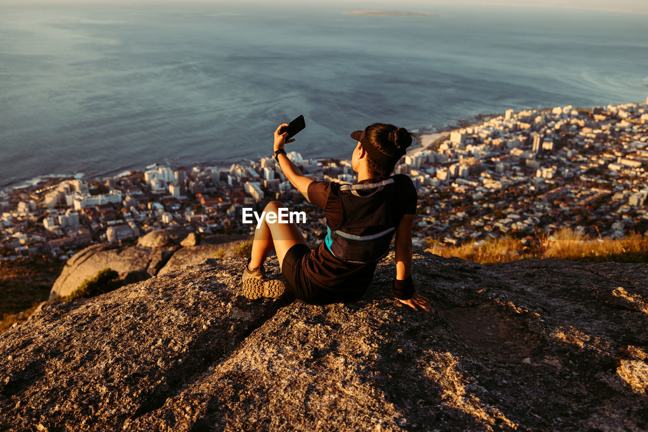 full length of woman sitting on rock at beach