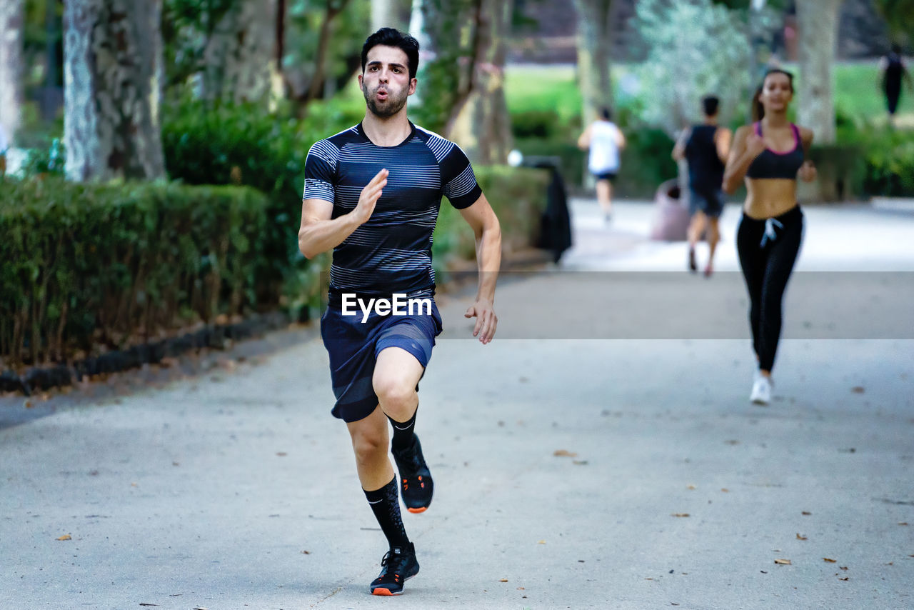 Full length of young man running on footpath