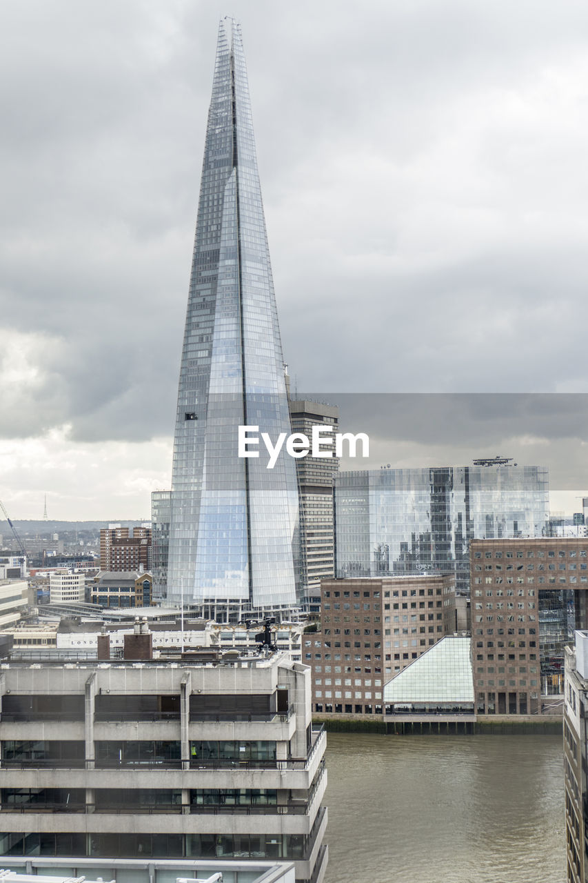 Modern buildings in city against cloudy sky