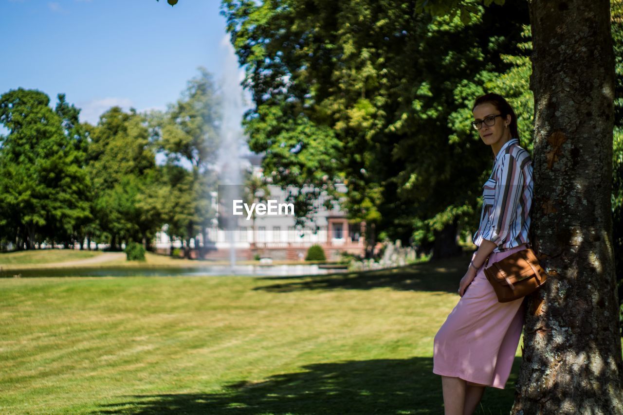 Portrait of young woman standing against trees