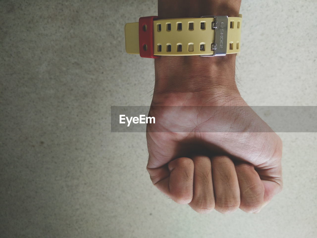 Cropped hand of man wearing wristwatch against wall