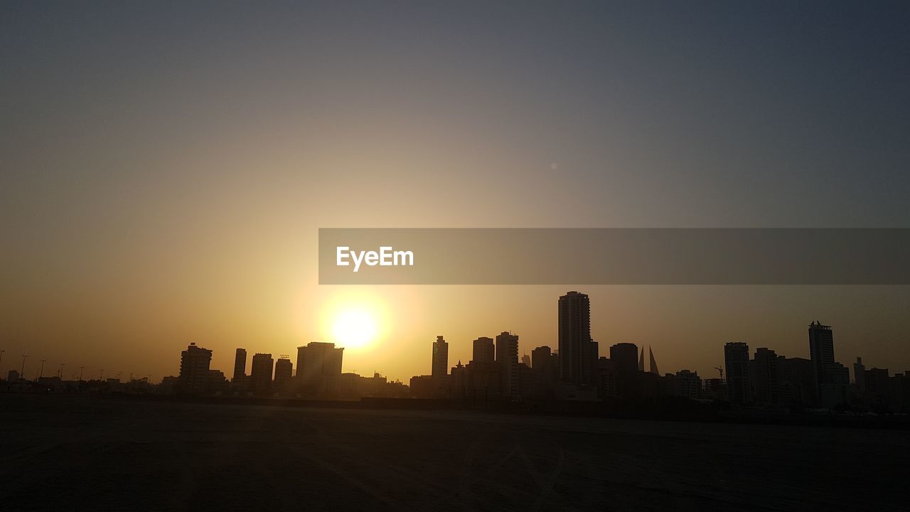 SILHOUETTE BUILDINGS AGAINST SKY AT SUNSET